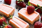 Von oben köstliche reife Erdbeeren und Minzblätter auf rosa Schokoladentäfelchen gelegt