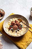 Hoher Winkel der Schüssel mit leckeren Milch Haferflocken mit knusprigen Schokolade Kugeln Kürbiskerne und Pekannuss auf Serviette für gesundes Frühstück serviert