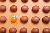 Muster aus ganzen braunen Eiern in gleichmäßigen Reihen mit rohen Eiern auf einem Pfirsichtisch im Atelier von oben