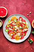 Draufsicht auf gesunden Salat mit Orangen, Erdbeeren, Äpfeln und Gurken, serviert mit Käse und Pistazien auf einem Teller