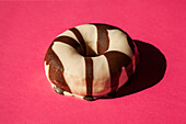White donuts coated oreo chocolate cookie pieces on pink background
