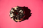 White donuts coated oreo chocolate cookie pieces on pink background