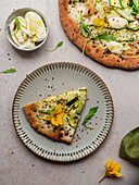 Overhead view of appetizing slice of pizza with arugula leaves and squash flower on melted cheese on gray background
