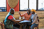 Company of content African American friends gathering at table with beer in bar and talking to each other