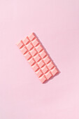 Ansicht von oben minimalistische Komposition mit Stücken von handgemachten rosa Schokolade bar auf rosa Hintergrund