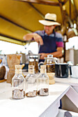 Soft focus of corked small bottles of coffee grains placed on table in country house on blurred background of bartender