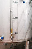 Edelstahlbehälter mit Aräometer mit Zahlen und Skala gegen Flüssigkeit im Schlauch in einer Bierfabrik