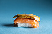 Traditionelle japanische Delikatessen Norwegische Nigiri mit frischem Lachs und schmackhafter flambierter Gänsestopfleber, serviert vor blauem Hintergrund in einem hellen Studio