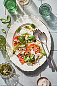 Top view of appetizing Spanish salad with assorted ingredients and tomatoes served on ceramic plate with spoon