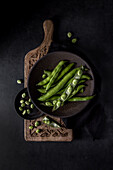 Top view of composition of two bowls with organic raw French beans and legumes on decorative cutting board