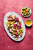 From above fresh ripe grapes, olives, figs and mozzarella seasonal christmas salad placed on plate on red tabletop background