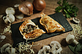 From above of appetizing argentinian empanadas served on flat plate on wooden table near ingredients in kitchen