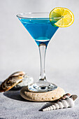 Glass of blue kamikaze drink on stone in modern style