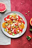 Draufsicht auf gesunden Salat mit Orangen, Erdbeeren, Äpfeln und Gurken, serviert mit Käse und Pistazien auf einem Teller