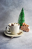 Becher mit heißer Schokolade und Mini-Marshmallows mit Gewürzen auf weihnachtlich dekoriertem Hintergrund