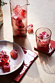 From above of tasty fresh cold drink made of frozen cubes with red flowers and herbs served in glass