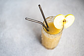 From above fresh apple smoothie served in glass with sliced apple on concrete background