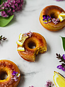 From above of yummy doughnuts with fresh lemon slices and Lavandula flowers on marble surface