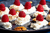 Appetizing delicious creamy dessert with fresh ripe raspberries with pecan nuts placed on plate in cafe