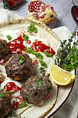 Traditionelle hausgemachte Rind- und Lammfleischbällchen mit arabischem Brot, Tomatensauce, Granatapfel und Kräutern. Halal-Essen