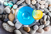 Glass of blue kamikaze drink on stones in modern style