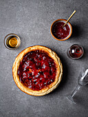 Leckerer hausgemachter süßer Käsekuchen von oben auf einem grauen Tisch vor einem Glas mit Soßen und einer Schale mit Marmelade