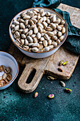 From above organic and raw pistachio nuts in the bowls on green table background