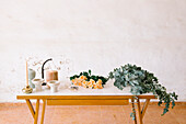 Bunch of fresh aromatic roses and Eucalyptus leaves placed on table near candle vases and jute thread spool in floral atelier