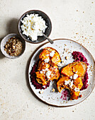 Top view of appetizing toasts with pumpkin slices and curd served on plate near bowl with cheese