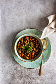 Vegetarische Bohnensuppe, serviert in einer Keramikschale mit Zwiebel und Korianderkraut