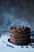 Delicious chocolate cake with chocolate glaze and blueberries served on plate on gray background