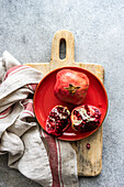 Organic ripe pomegranate fruit on red ceramic plate on stone background