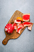 Top view of delicious peeled red orange placed near peel on wooden cutting board