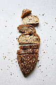 Top view of appetizing homemade sliced bread with crispy crust and seeds on top placed in white surface