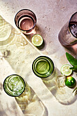 Draufsicht auf einen erfrischenden Mojito-Cocktail mit Eiswürfeln, Limette und Minze im Freien an einem sonnigen Sommertag