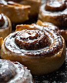 Appetizing baked sweet cinnamon rolls with white cream topping served on table in bakery