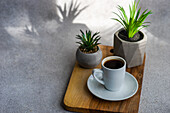 Morning cup of black coffee or espresso on the stone table with green plants in concrete pots