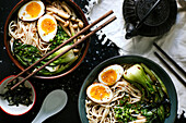 Blick von oben auf Keramikschalen mit köstlichen Ramen und Essstäbchen auf dem Tisch