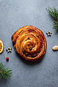 Top view of delicious homemade baked snail pastry placed on grey board with Christmas decoration around