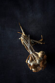 From above bouquet of fresh purple garlic cloves placed in dark background