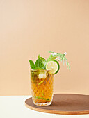 Glas köstlicher alkoholfreier Cocktail mit Limetten- und Zitronenscheiben, dekoriert mit Minzblättern auf einem Holzbrett