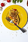 Delicious omelette with chopped parsley on plate against sun dried tomatoes on white background