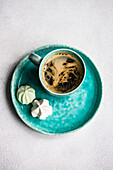 from above cup of coffee with mini sweets on concrete table