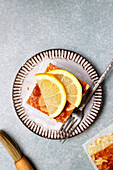Top view of square slice of delicious homemade lemon cake served on plate with fork on tray