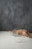 Glass cup and cloth placed with tree twig on beige and gray background