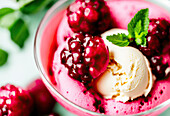 Appetizing frozen sorbet with vanilla ice cream scoop and raspberries decorated by mint leaves on table