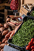 Von oben grüne Bohnen, Süßkartoffeln und Tomaten an einem Stand auf einem lokalen Markt