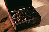 From above of freshly roasted aromatic coffee beans in wooden box of antique grinder placed on table in daylight