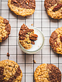 Top view of appetizing walnut cookies in glass on milk and on baking net served on table