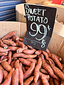 From above of raw sweet potatoes in carton box placed on stall in local market